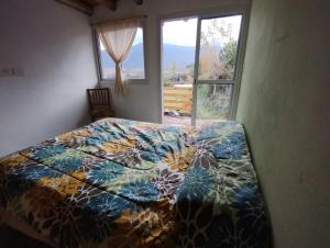 且乌塔Vista los Andes的卧室里一张带五颜六色棉被的床,卧室里设有窗户