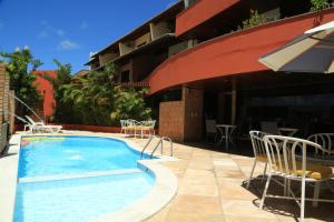 纳塔尔Garbos Soleil Hotel的一座带椅子的游泳池以及一座建筑