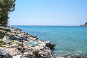 阿利基Petra Mare Apartments的岩石海岸上的蓝色躺椅