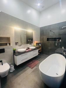 雷克霍特Luxury villa with hot tub & amazing view的一间带两个水槽、一个浴缸和两个卫生间的浴室