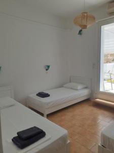 伊奥斯乔拉Zinas pension的白色的客房设有床和窗户。