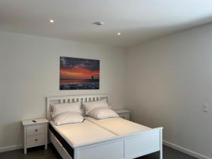 比苏姆Ferienhaus RELAX的卧室配有一张白色床,墙上挂有绘画作品