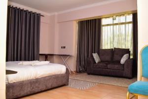 纳库鲁RAVIC HOMES NAKURU的一间卧室配有一张床、一张沙发和一把椅子