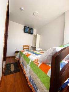 基多Hostal La Terraza的卧室配有一张床,墙上配有电视。