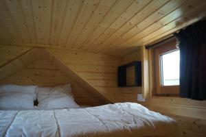 La BoissièreSpa & Bain Nordique - Tiny house à la campagne的木制客房的一张床位,设有窗户