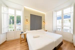 特里亚卡斯特拉Hotel Alda Triacastela的一间白色卧室,配有床和2个窗户