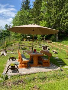Nötsch bei BleibergWaldhütte Glück Auf的一张带雨伞和长凳的野餐桌