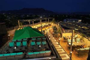 阿杰梅尔HOTEL AJMER SHERATON的一个带绿色遮阳伞和桌椅的屋顶露台
