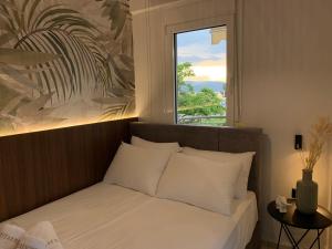 奥弗里安Vryzas Resort的窗户客房内的一张带白色枕头的床