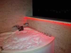 贝尔格莱德Rooms Green Set的一间带粉红色浴缸及红灯的浴室