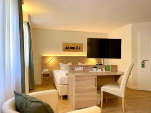 韦特海姆Hotel Bronnbacher Hof的酒店客房设有一张床和一张带电视的书桌。