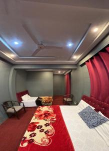 锡卡都Skardu Lodge的一间卧室配有一张床铺,床上铺有红色毯子