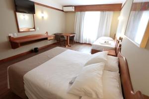 卡内拉Tri Hotel的酒店客房设有一张大床和一张书桌。