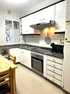 艾利亚德亚罗萨Apartamento Praia Naval的厨房配有白色橱柜和黑色台面