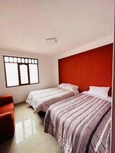 阿亚库乔Castellares la Puebla Hostelería Departamento的一间卧室设有两张床和红色的墙壁