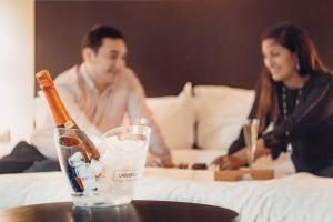 圣地亚哥圣地亚哥福朋喜来登酒店的坐在床上的男人和女人,带一瓶香槟
