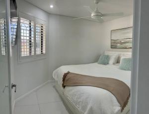 悉尼Bondi Beach Waves Beachfront Apartment的白色卧室配有床和吊扇