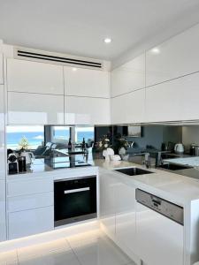 悉尼Bondi Beach Waves Beachfront Apartment的厨房配有白色橱柜和水槽