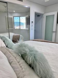 悉尼Bondi Beach Waves Beachfront Apartment的一间卧室配有一张带白色床单和镜子的床