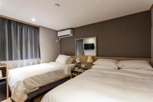 首尔About Stay Seoul的酒店客房设有两张床和窗户。