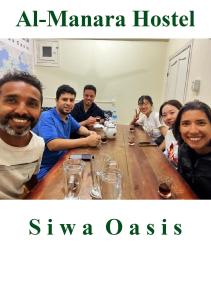 锡瓦Al-Manara Hostel Siwa Oasis的一群人坐在木桌旁