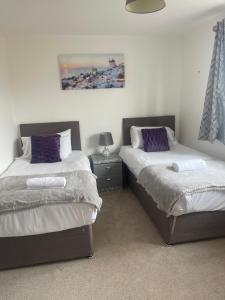 Higham FerrersSteeple House的一间卧室配有两张带紫色枕头的床