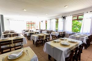 阿瓜斯迪林多亚Hotel Fazenda Aguas de Lindoia的餐厅设有白色的桌椅和窗户。