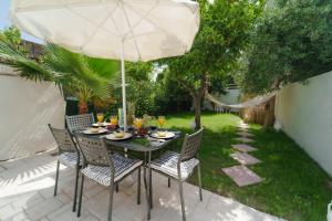 扎金索斯镇Karydakis Properties的庭院内桌椅和遮阳伞