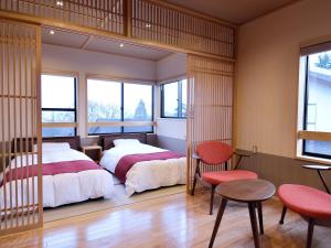 AkakuraRyokan Okayama的一间卧室配有两张床和一张桌子及椅子