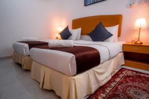马斯喀特العاصمة للشقق الفندقية - Capital Hotel Apartments的红色地毯的酒店客房内的两张单人床