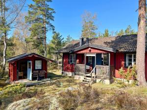 DalaröHoliday home ORNÖ II的红色小屋,在树林里设有门廊