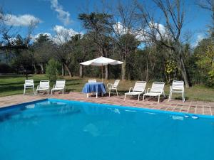诺诺Rincón Alto Cabañas的游泳池旁配有桌椅和遮阳伞