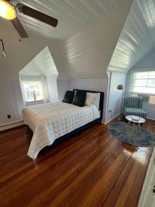奥克布拉夫斯Inkwell Beach Cottage的一间卧室配有一张床和一把椅子,铺有木地板
