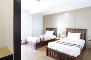 曼谷纳南泰套房酒店的一间卧室配有两张带白色床单的床