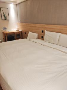 永和浮逸饭店的卧室配有一张白色大床和木制床头板