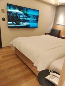 永和浮逸饭店的酒店客房设有一张床铺,墙上配有电视