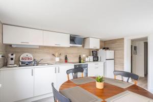 鲁瓦扬Appartement 200 m plage avec terrasse et jardin的厨房配有白色橱柜和桌椅