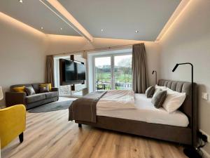 泰克伦堡DRIEHOF LandGut & Residenz LifeStyle-Comfort Apt 7的一间卧室配有一张床、一张沙发和一台电视