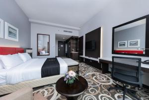 古晋Raia Hotel & Convention Centre Kuching的酒店客房设有一张大床和一张书桌。