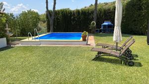 马拉加Casa Rural Cupiana Piscina privada Malaga的游泳池旁的椅子和遮阳伞
