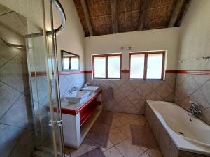 法尔瓦特Izintaba Private Game Reserve Waterberg的浴室配有2个盥洗盆、浴缸和淋浴。
