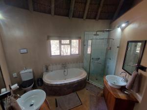 法尔瓦特Izintaba Private Game Reserve Waterberg的带浴缸、两个盥洗盆和淋浴的浴室。