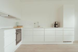 托尔斯港Nordic Swan Aparthotel with Panoramic Seaview的白色的厨房配有白色橱柜和电器