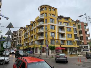 索非亚Niko's deluxe apartment的一座黄色的建筑,前面有汽车停放