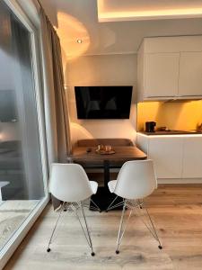 泰克伦堡DRIEHOF LifeStyle Comfort Apt 4的厨房里配有两把白色的椅子和一张桌子
