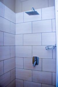 龙杜Home@Amalia’s的白色瓷砖浴室设有淋浴和肥皂架