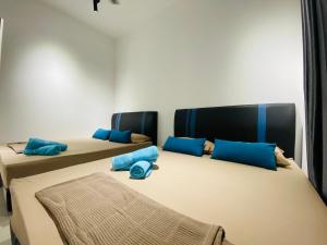 山打根Proboscis Guest House的配有蓝色枕头的客房内的两张床
