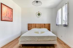 纳博讷La Villa d'Isa et Seb的白色卧室配有一张带木制床头板的床