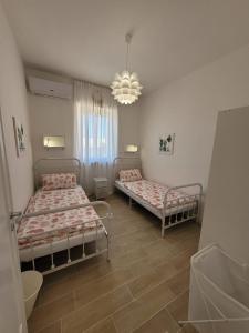 丽都玛里尼Appartamento Demetrio 50m mare & shopping的一间卧室配有两张床和吊灯。