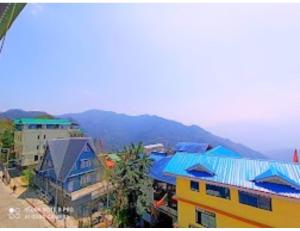 NamchiHotel Maurya Residency, Namchi的一群拥有蓝色屋顶和山脉的建筑
